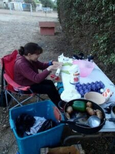 Woman preparing food outdoors on a table.