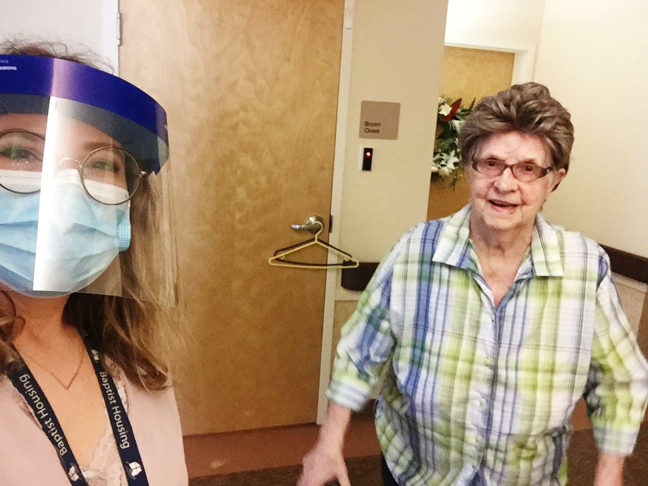 Caregiver and elderly woman smiling indoors.