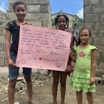 Children holding thank you sign at construction site.