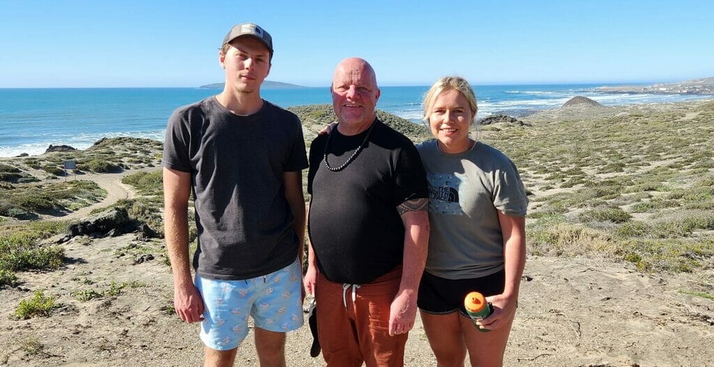 Three people standing on a coastal trail.