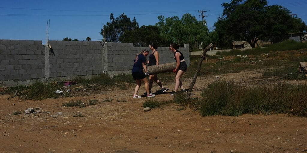 Three people carrying a heavy object outside.