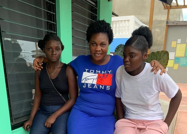 Three people sitting outside a colorful building.