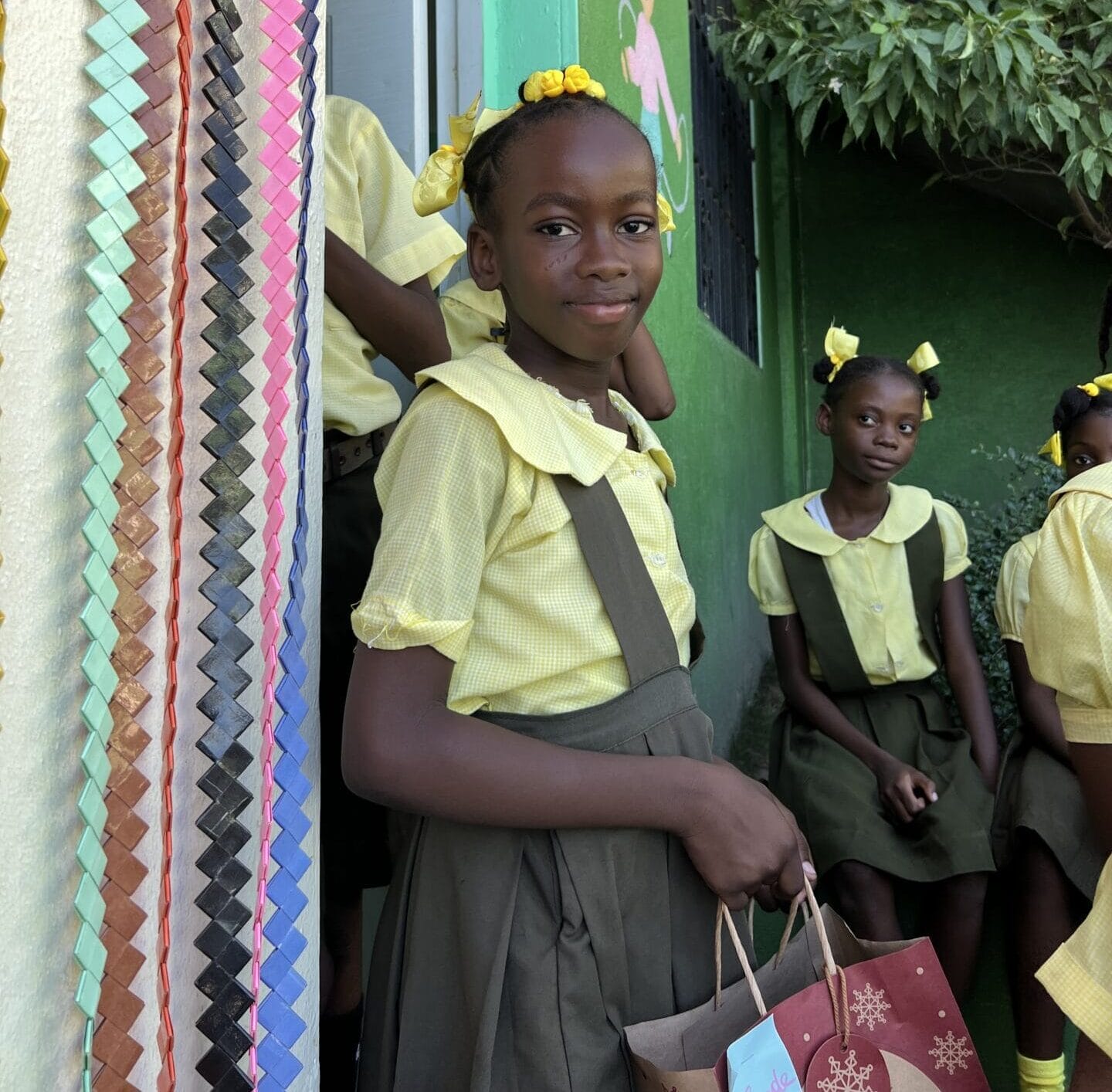 Girls in yellow uniforms holding gift bag.