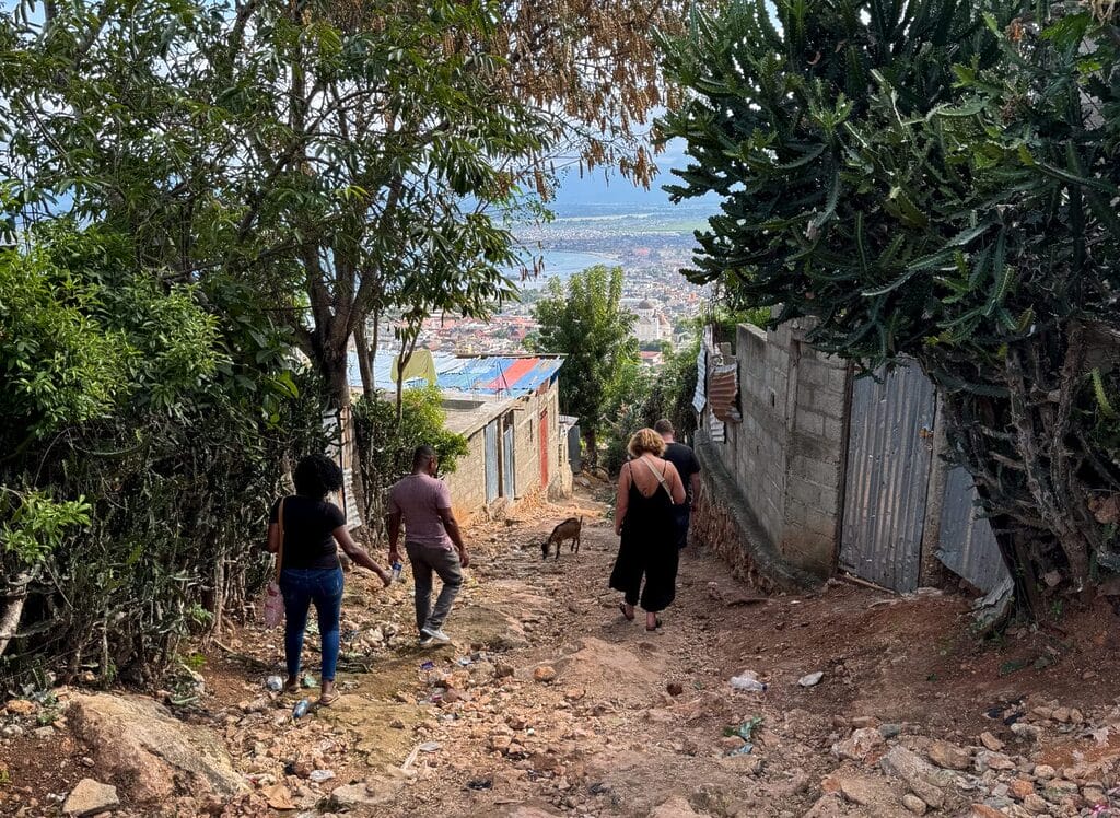 People walking down rocky hill with city view