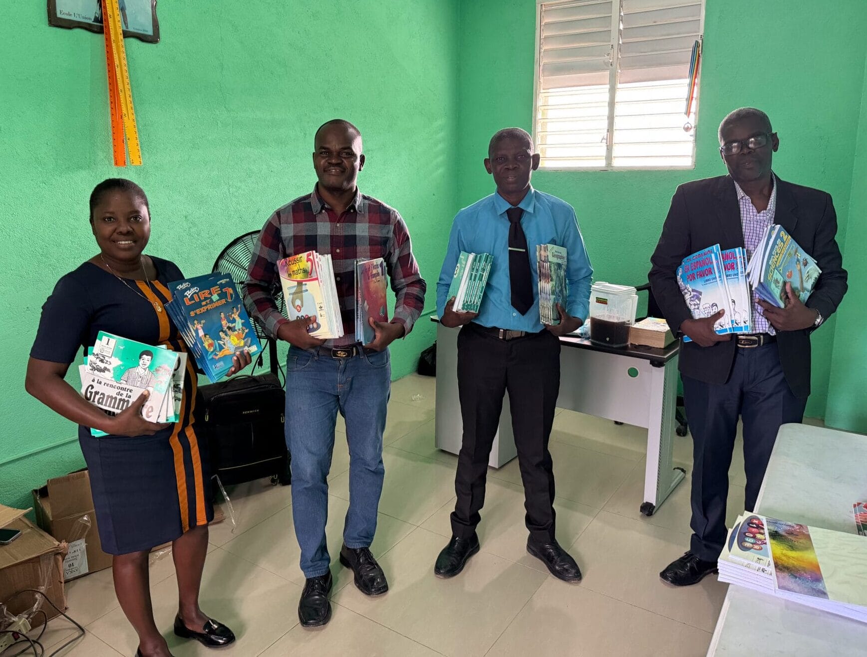 Four people holding educational books in a classroom.