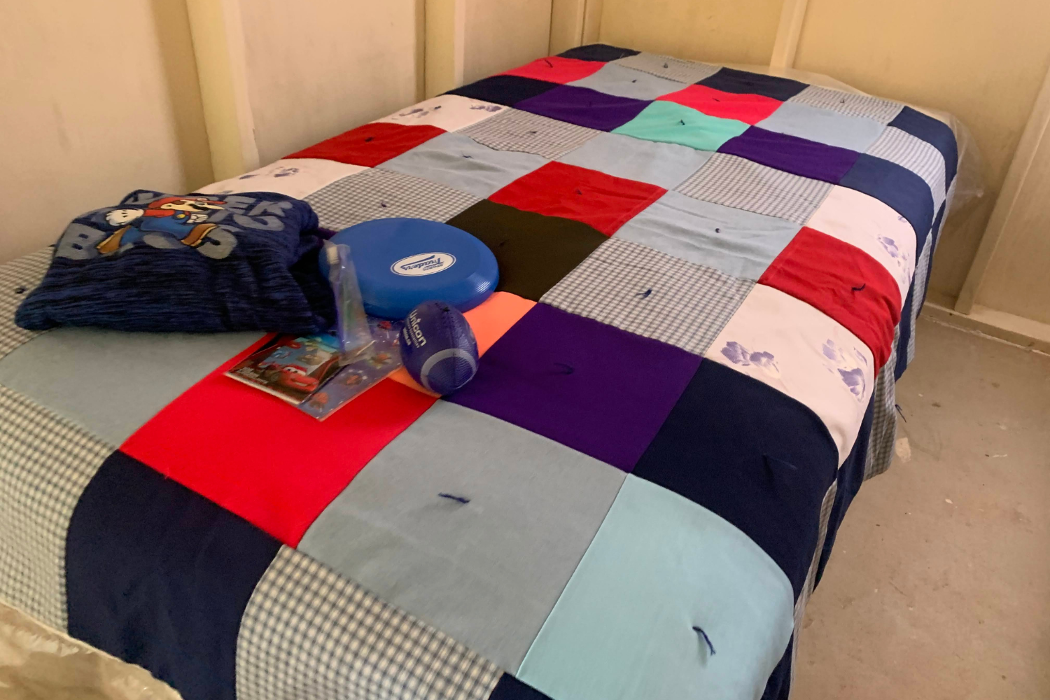 Colorful patchwork quilt with toys on bed.