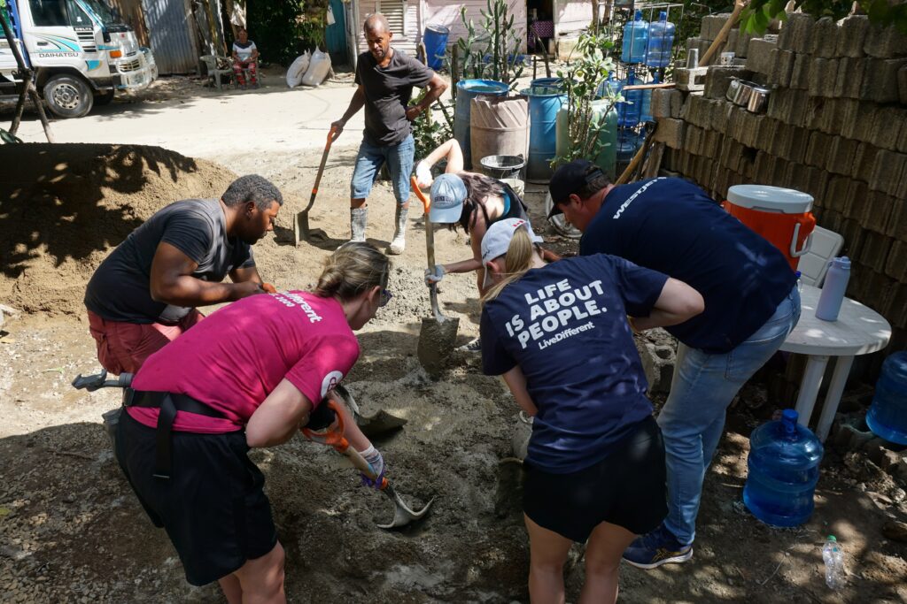 Group volunteering, shoveling sand outdoors.